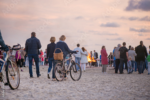 Romantic bonfire night at seaside during sunset. People gathering together to celebrate Night of ancient lights. Large burning campfire with soft glowing flame and sparkles in the background