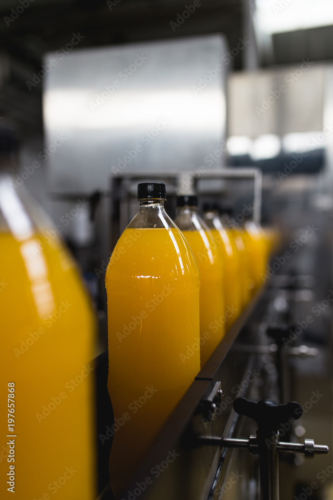 Bottling factory - Orange juice bottling line for processing and bottling juice into bottles. Selective focus. 