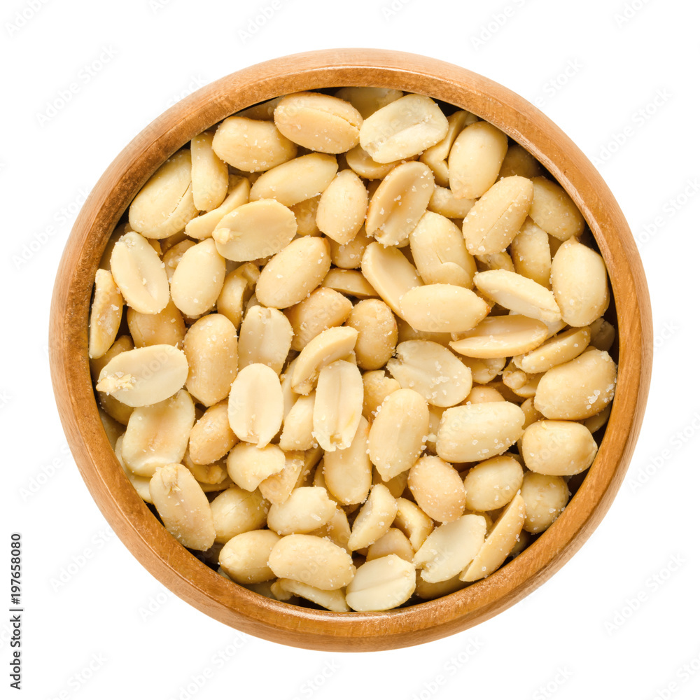 Peanuts, roasted and salted, in wooden bowl. Shelled Arachis hypogaea, also called groundnut and goober, used as a snack. Isolated macro food photo close up from above on white background. Peanuts, roasted and salted, in wooden bowl. Shelled Arachis hypogaea, also called groundnut and goober, used as a snack. Isolated macro food photo close up from above on white background.
