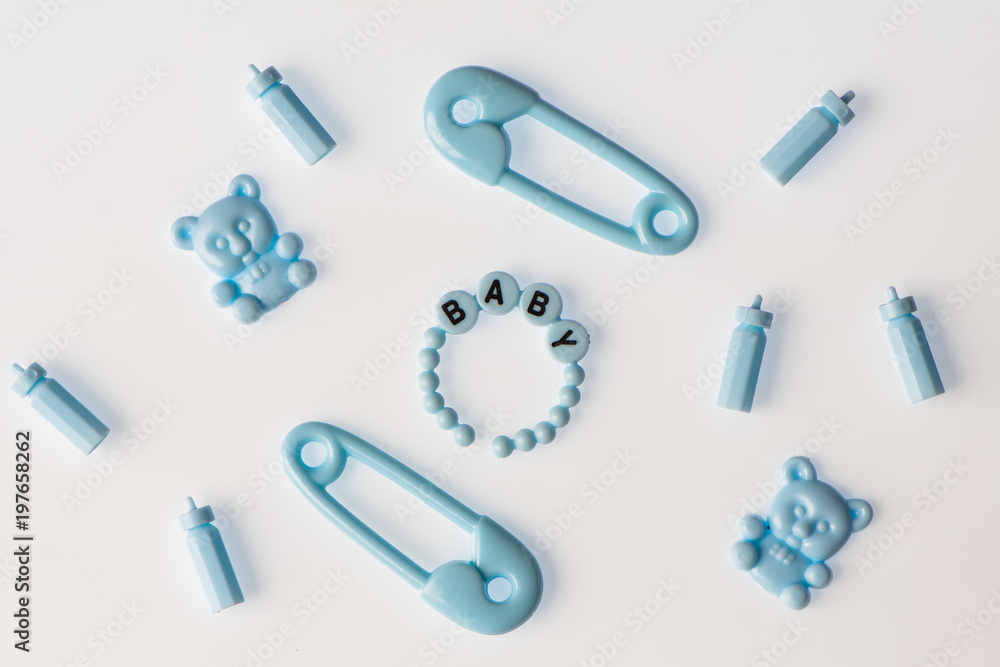 Flat lay of blue baby items - bears, bottles, safety pin