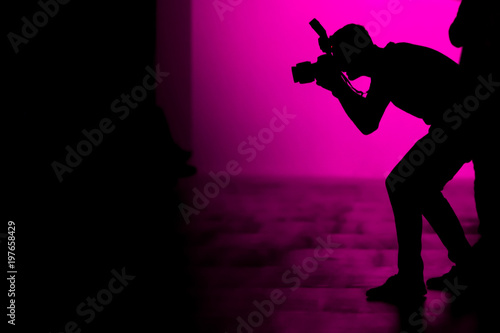 Silhouette of a photographer taking photographs of celebrities on the fashion show.