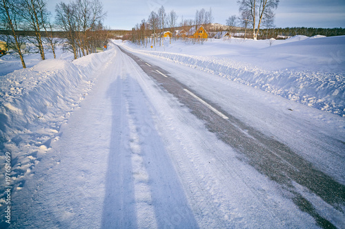 A never-ending journey. Wide winter road with snow and the shadow of two people on frosty evening