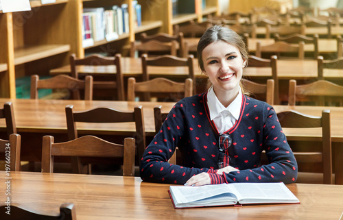 Portrait of concentrated student studying in library, young good-looking woman reading books attentively