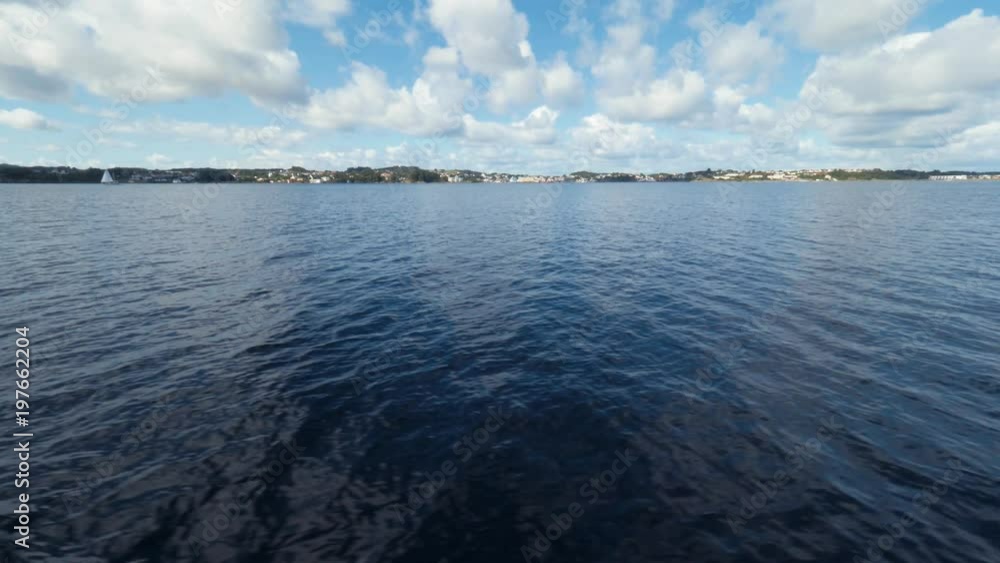 Aerial tracking shot. Smooth surface of beautiful pond. Slow motion. Magnificent landscape of Norwegian fjord. Typical small fishing town in the middle of the sea in Norway. View from side deck ship Aerial tracking shot. Smooth surface of beautiful pond. Slow motion. Magnificent landscape of Norwegian fjord. Typical small fishing town in the middle of the sea in Norway. View from side deck ship