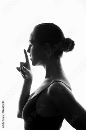 Profile of young atletic girl with forefinger close to her face (silence sign) photo