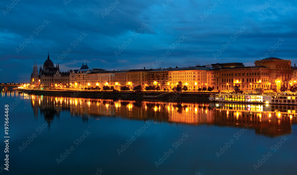 Pest downtown riverfront at night, reflecting in still Danube water. Budapest, Hungary