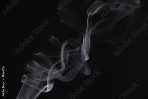 Smoke from an incense stick, which forms strange shapes, on a black background. 