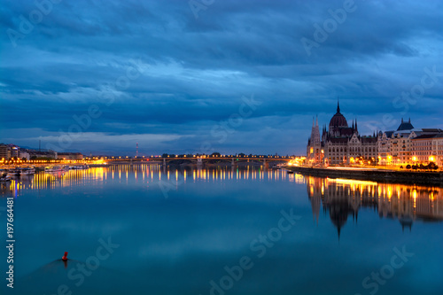 Still Danube river at dawn, reflected highlighted shores, Parliament domes. Budapest, Hungary