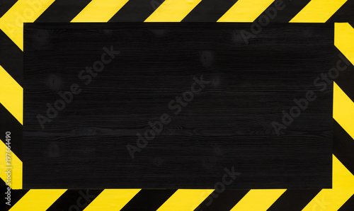 Under construction concept background. Warning tape frame on black wooden surface background with copy space.