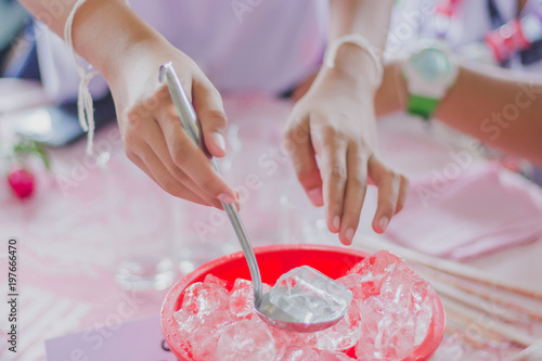 Close-up th hands add ice to the glass to distribute to friends at the table on party of Graduation.