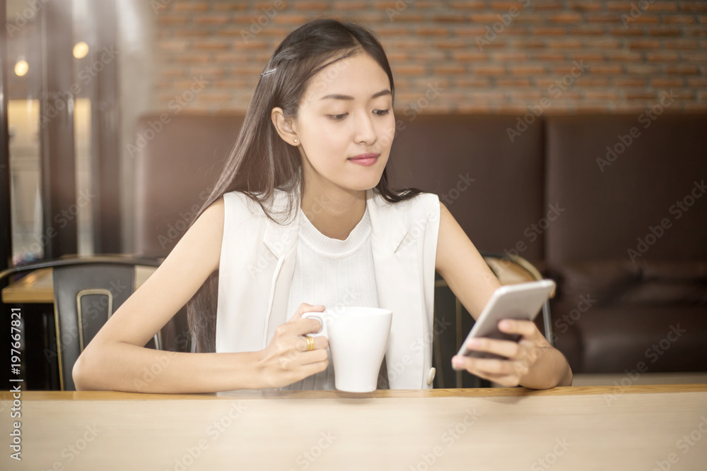 Smiling Asian girl with a cup of coffee sitting in cafe Smiling Asian girl with a cup of coffee sitting in cafe