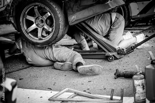 Mechanics lying and working under the driftcar