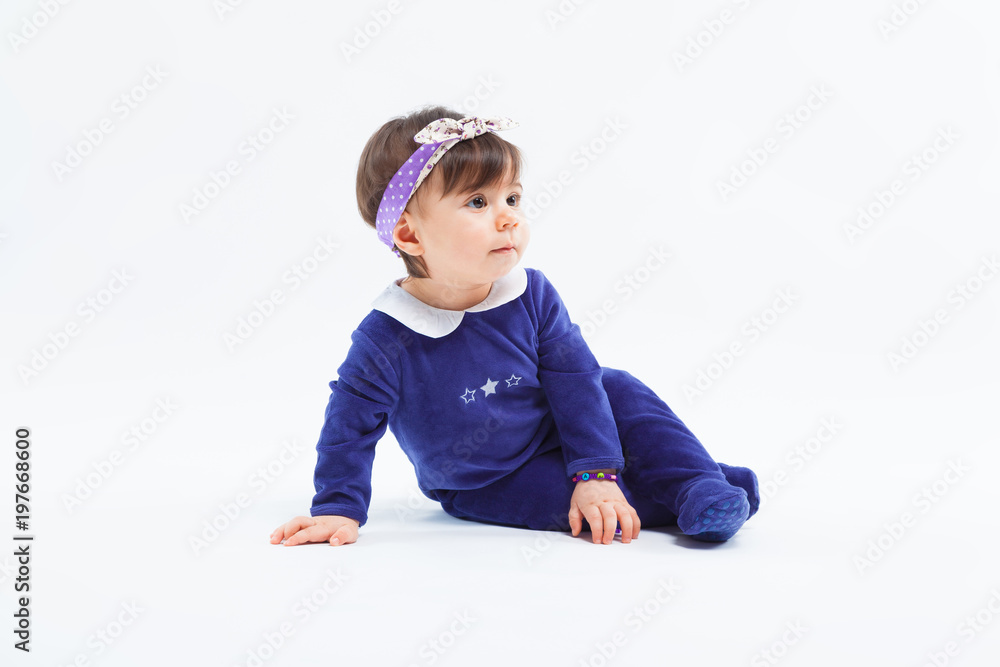 Little cute adorable girl with bow in hair sitting in studio posing on white background Little cute adorable girl with bow in hair sitting in studio posing on white background