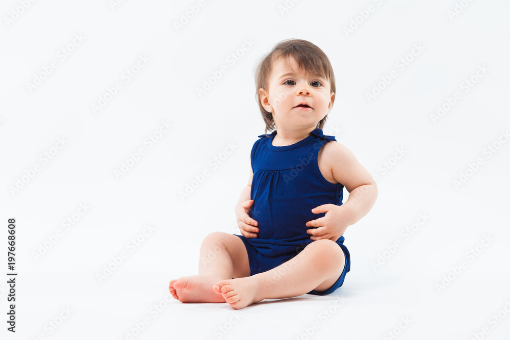 Cute funny small smiling girl sitting in studio posing on white background Cute funny small smiling girl sitting in studio posing on white background
