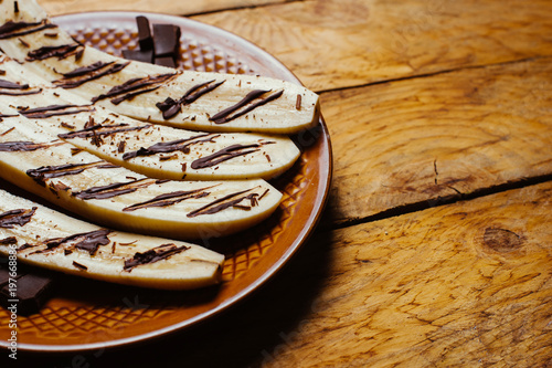 Baked banana dessert with chocolate on plate  on wooden background table.  Recipe menu restaurant photo