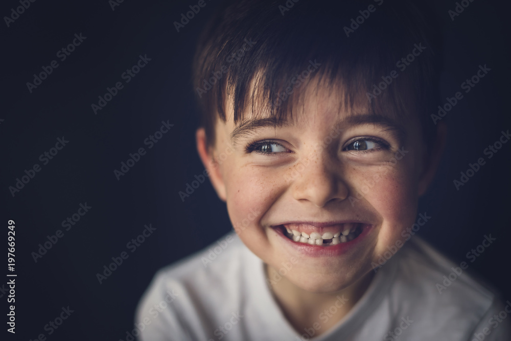 Cheerful boy with gap toothed looking away in darkroom Cheerful boy with gap toothed looking away in darkroom
