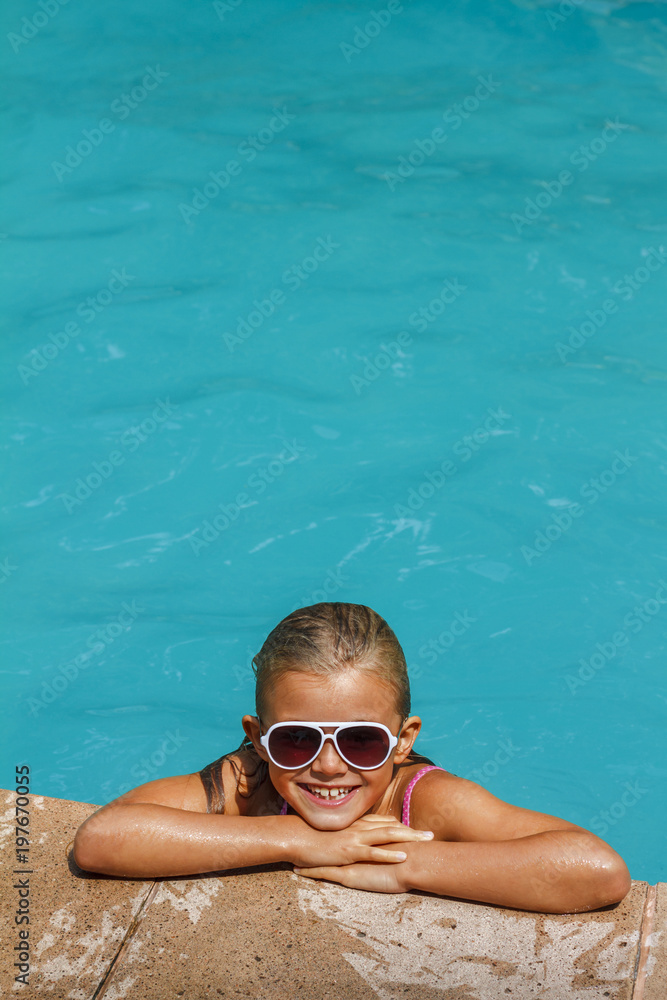 Pretty smiling girl in swimming pool on resort