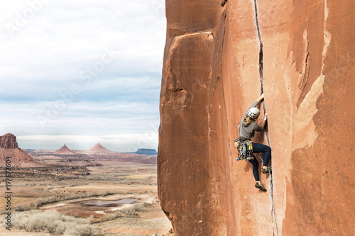 Rear view of female hiker rock climbing against cloudy sky