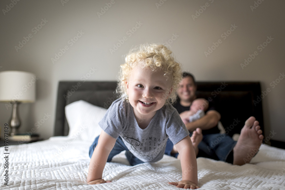 Portrait of boy with father carrying brother on bed at home Portrait of boy with father carrying brother on bed at home