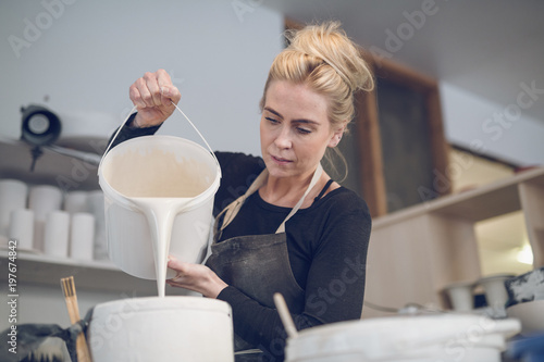 Woman pouring paint in container at workshop photo