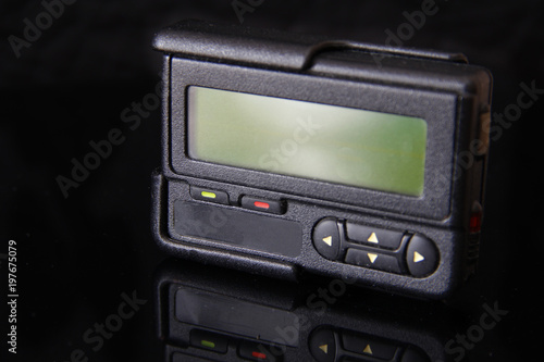 Old black pager or beeper isolated on black background. Vintage gadget for communication device © Andrey