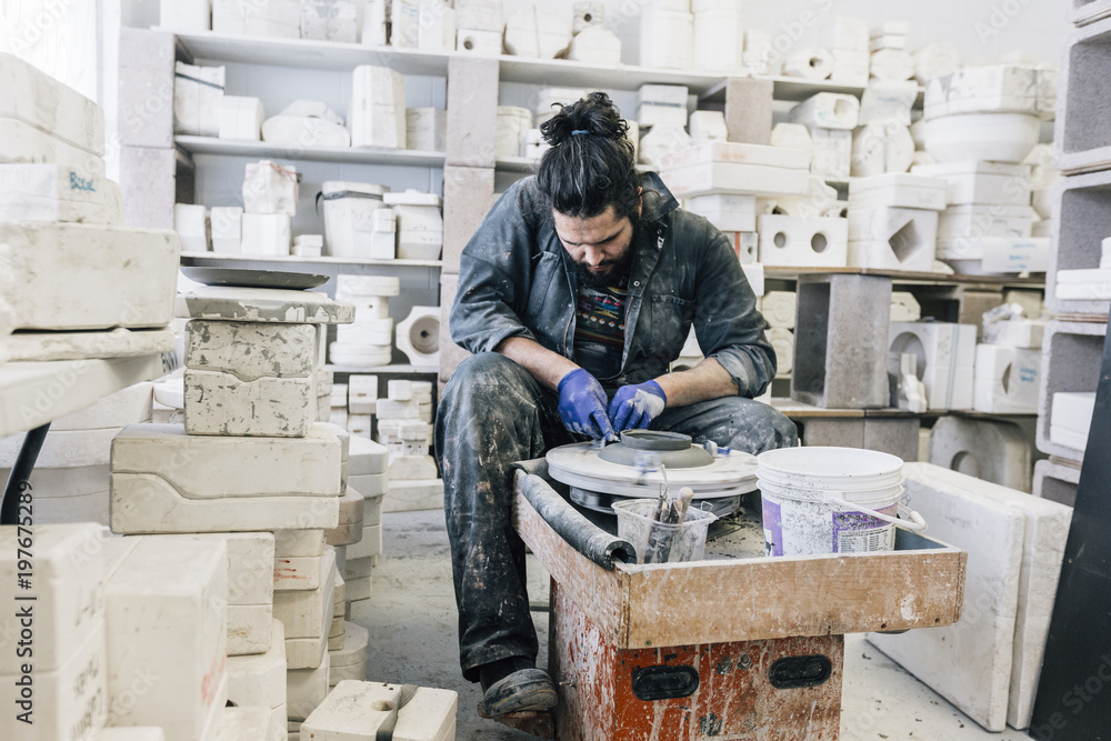 Craftsman using pottery wheel while working in workshop Craftsman using pottery wheel while working in workshop