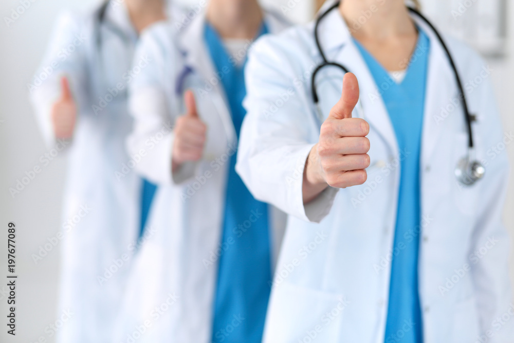 Groupe of medicine doctors show OK sign with thumb up close up. Success and high level service in health care, best treatment and customer loyalty and physical concept. Copy space for advertisement Groupe of medicine doctors show OK sign with thumb up close up. Success and high level service in health care, best treatment and customer loyalty and physical concept. Copy space for advertisement