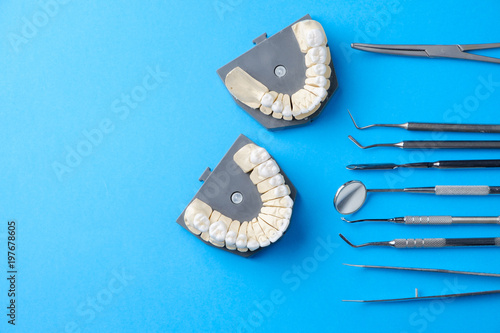 Denta metall tools, mirror, spatula, dental prints on a blue background, top view photo