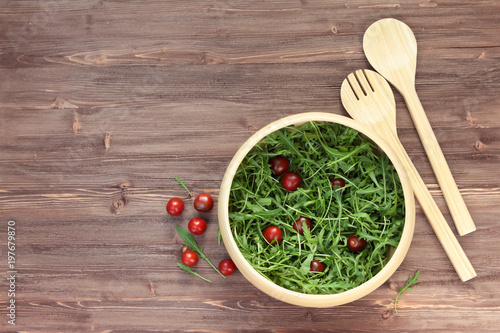 salad bowl, arugula, tomatoes on a wooden background