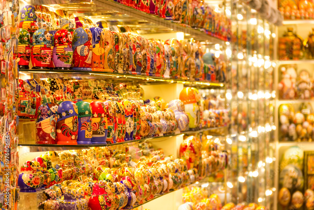 Obraz premium A lot of matreshkas at souvenir market shop. Different colors Russian dolls. Traditional classic Russian handicraft art background. Famous classical and modern russian dolls matreshka toys