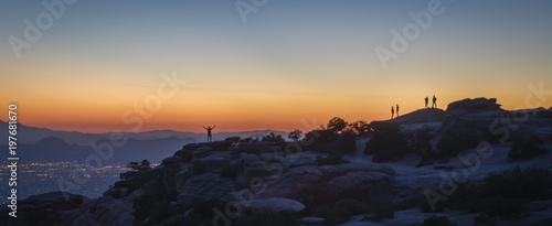 A man with hand held skyward is captured against distant mountains at sunset. Tucson, Arizona.