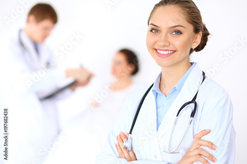 Cheerful smiling female doctor on the background with physician and his patient in the bed