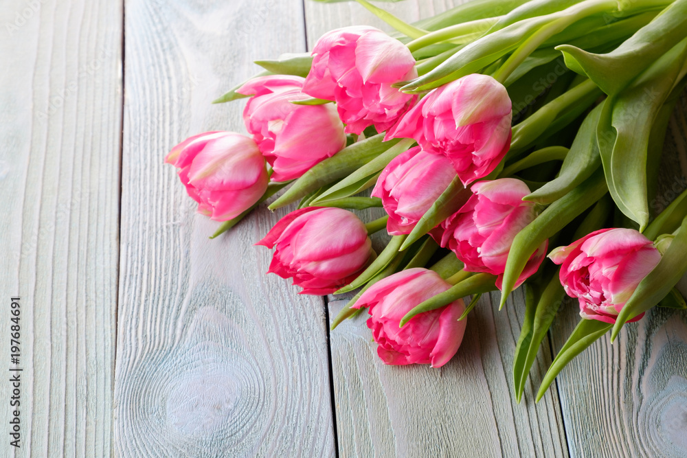 Bouquet of pink fresh tulips on a wooden table, top view