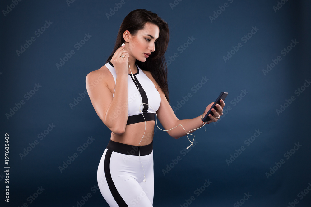 Stop wishing, start doing! Beautiful athletic young girl wearing modern sport clothes and listening to music in her headphones in order to make sport exercise easier. Stop wishing, start doing! Beautiful athletic young girl wearing modern sport clothes and listening to music in her headphones in order to make sport exercise easier.