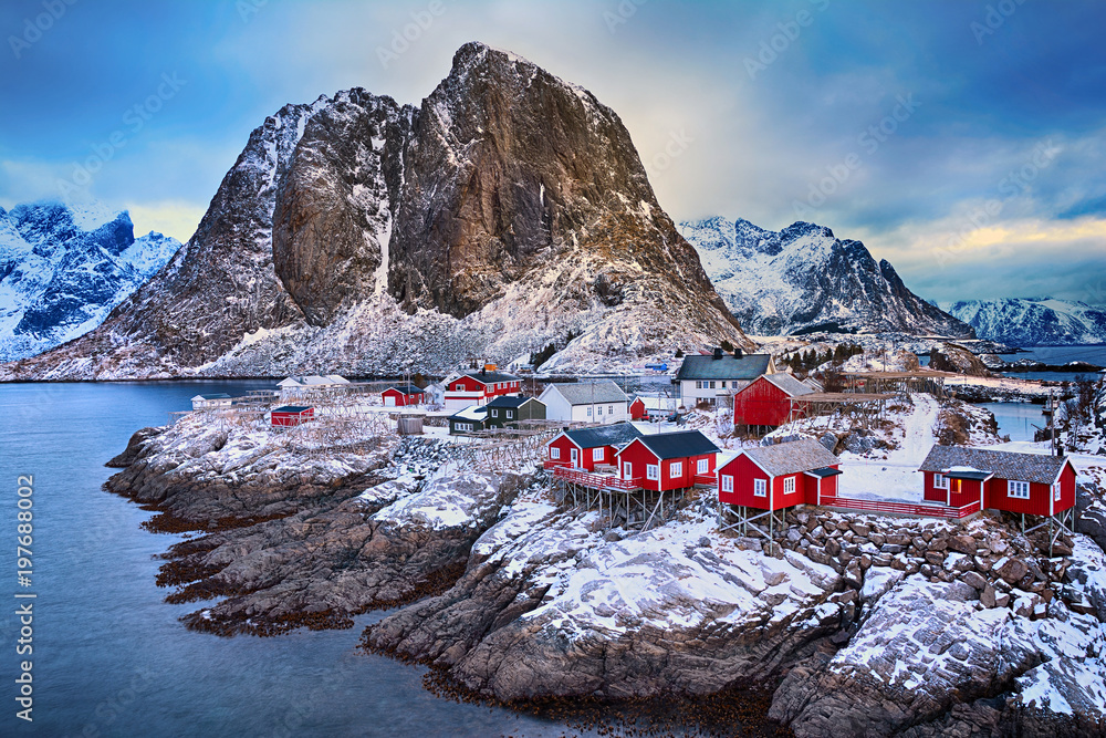 Winter landscape of picturesque fishing village with red rorbus in the mountains of Lofoten islands