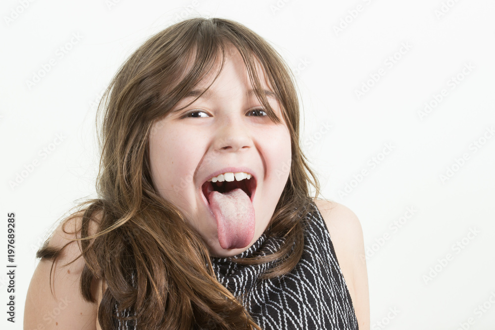 Angry little girl shows her tongue in funny grimace Angry little girl shows her tongue in funny grimace