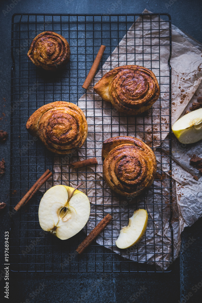 cinnamon rolls on the stone table, decoration with apples and cinnamon cinnamon rolls on the stone table, decoration with apples and cinnamon