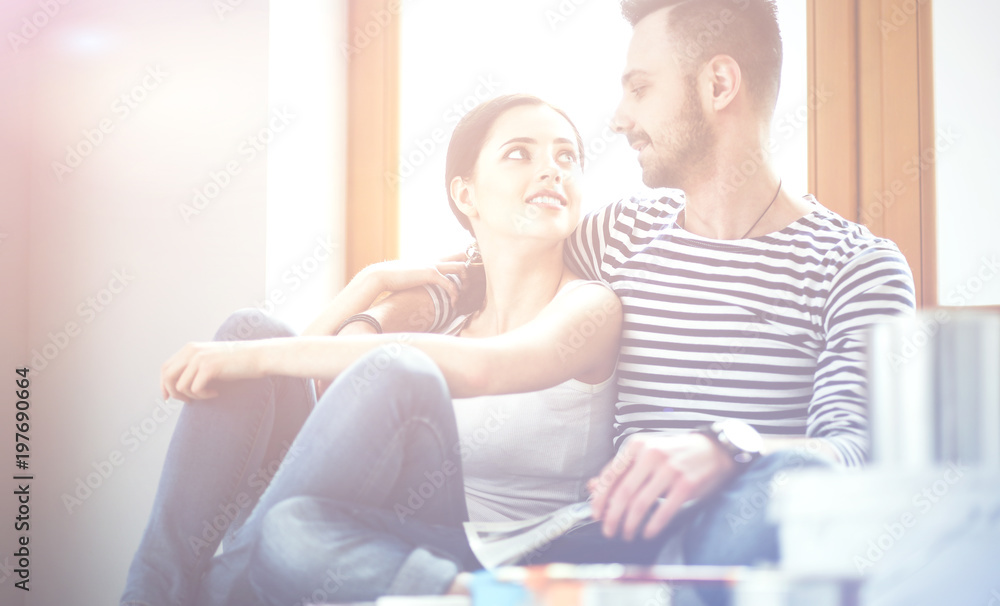 Attractive couple sitting on home floor looking at jurnal and smiling at each other. Attractive couple sitting on home floor looking at jurnal and smiling at each other.
