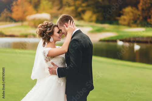 Newlyweds looking each other with tenderness and love. a couple standing on the background of a lake and an autumn forest