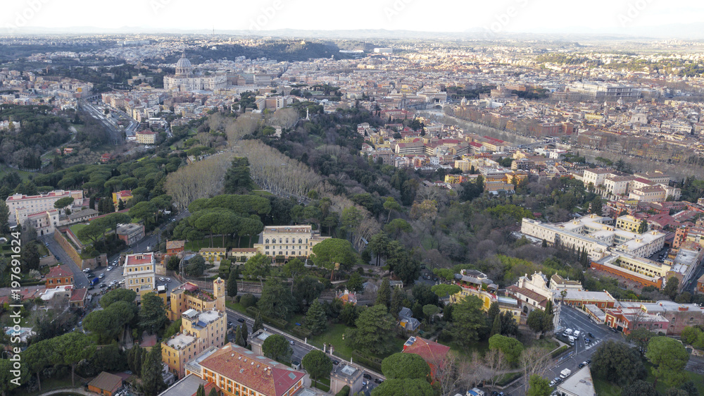 Panoramic aerial view of the northern area of Rome, Italy, on a sunny day. You can see a part of the river Tiber and in the background the dome of St. Peter's Basilica.