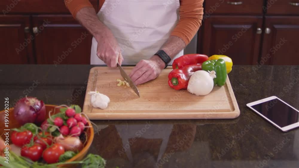Medium shot of a chef chopping up some garlic on a cutting board in a kitchen Medium shot of a chef chopping up some garlic on a cutting board in a kitchen