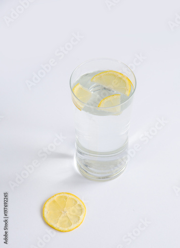 Glass of water with lemon slices on a white background