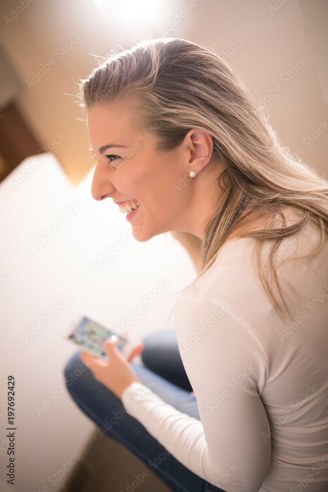 smiling beautiful woman using her mobile phone sitting on the floor in her home smiling beautiful woman using her mobile phone sitting on the floor in her home