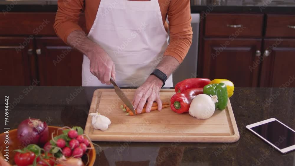 Medium shot of a chef chopping up some carrots on a cutting board in a kitchen Medium shot of a chef chopping up some carrots on a cutting board in a kitchen