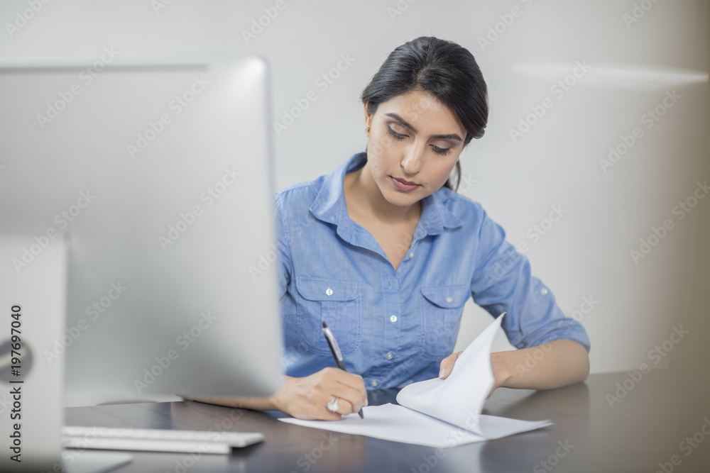 Businesswoman taking notes at desk in office Businesswoman taking notes at desk in office