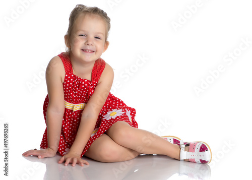 Little girl is sitting on the floor.