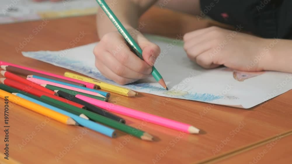 Close-up of unknown little girl draws the pictures using color pencils in the album in the kindergarten Close-up of unknown little girl draws the pictures using color pencils in the album in the kindergarten