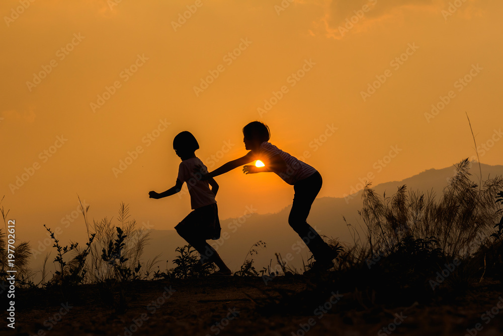 Silhouette happy two little girl playing at sunset background