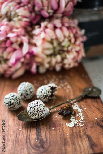 Sesame Coated Bliss Balls with Vintage Spoon and Flower Backdrop