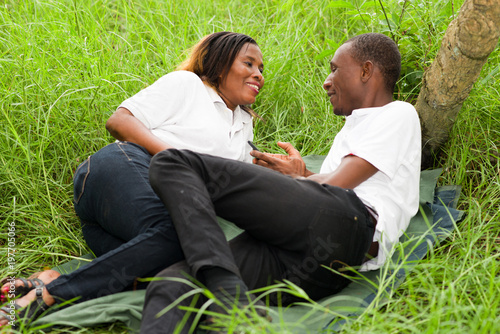 Happy couple lying on the grass using mobile phone © vystekimages